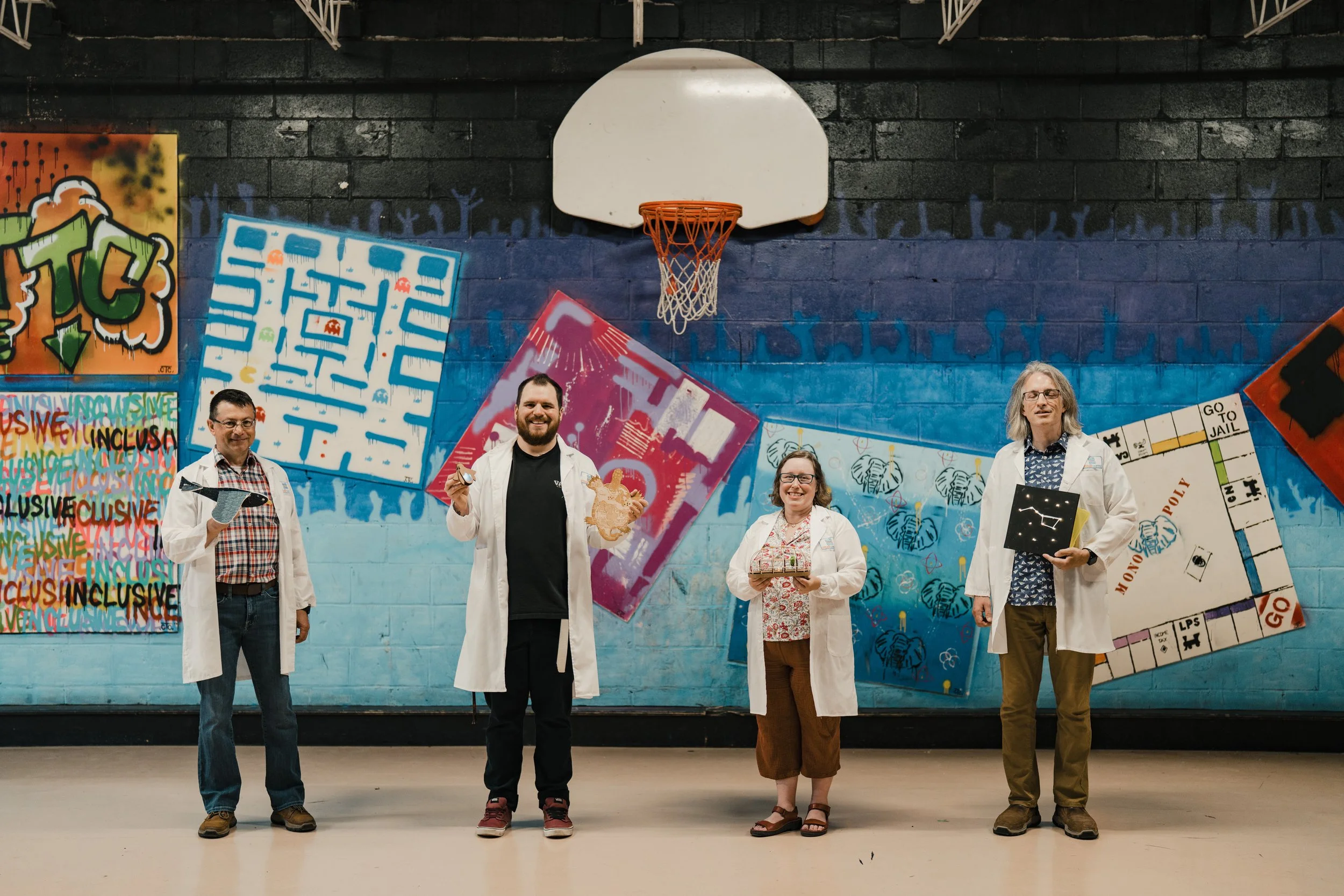 Four adults on a basketball court wearing white lab coats
