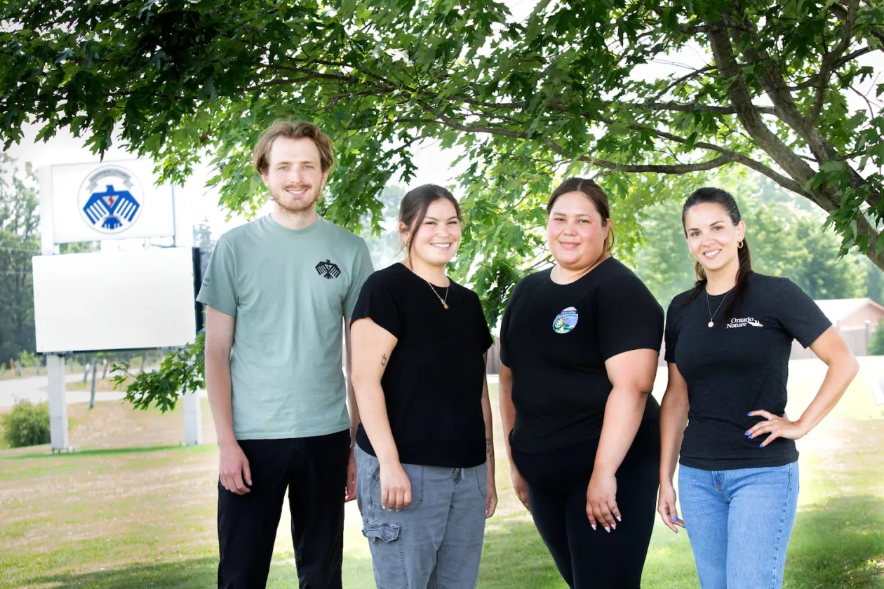 Four people standing under a tree